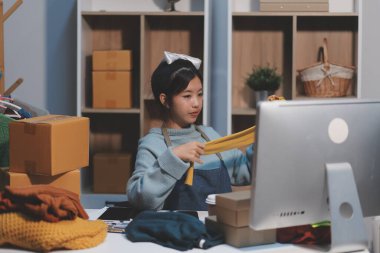 Genç Asyalı kadınlar müşterilerden gelen yeni siparişten sonra mutlu olurlar. Asyalı bir kadının online mağazasının satışındaki başarısının sürpriz ve şok edici yüzü. Çevrimiçi satış. Çevrimiçi Alışveriş