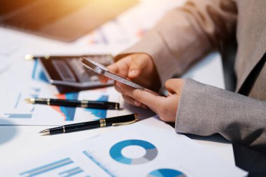 Hesap makinesi ve yazı kullanan bir iş kadını, hesap makinesiyle not alır. Ofiste çalışan bir kadın. Masasında dizüstü bilgisayar ve belgeler var.