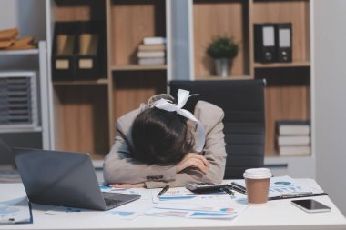 Genç Asyalı kadın migren ağrısı çekiyor. Ofiste dizüstü bilgisayarla çalışırken çok çalışan iş kadını finansörü..