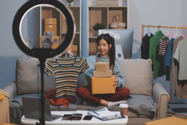 Genç Asyalı kadınlar müşterilerden gelen yeni siparişten sonra mutlu olurlar. Asyalı bir kadının online mağazasının satışındaki başarısının sürpriz ve şok edici yüzü. Çevrimiçi satış. Çevrimiçi Alışveriş