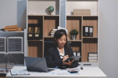 Genç Asyalı kadın portresi modern ofiste bilgisayar tableti üzerinde çalışıyor. Muhasebe analizi yapmak gayrimenkul yatırım verileri, mali ve vergi sistemleri kavramı.