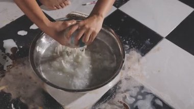 Kadın eli siyah lastik eldivenle mutfak sobasını temizliyor.