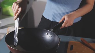 Kadın ocakta yemek pişiriyor.