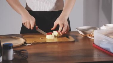 Bir kadın, tahta bir masada bıçakla turta hazırlıyor..