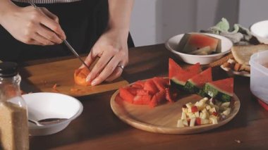 Kadın mutfaktaki masada taze sebze salatası yapıyor, yakın plan.