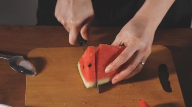 Kesme tahtasında karpuz kesen bir kadın..