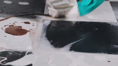 close up of female hand in black rubber glove holding brush and ink brush