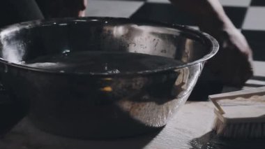 a vertical shot of a female hands holding a bowl with a white paint on a wooden table