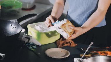 young woman preparing a sandwich in a kitchen.