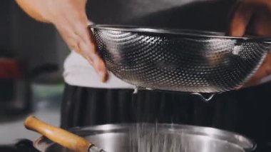 chef pouring fresh water from pan on cooking pan, close - up.