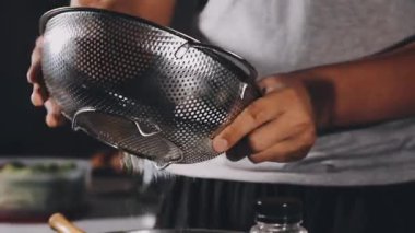 close up of a hand holding a bowl with a black pepper
