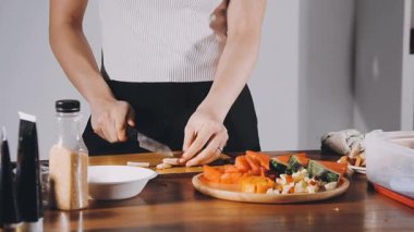 young woman cutting carrot salad in the kitchen