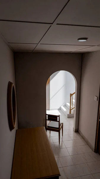 Minimalist 3D bir iç mekan, sandalye, ahşap mobilya ve kemer yolu boyunca doğal ışık. Yalnızlık, tasarım veya mimari sanat kavramları için mükemmel..