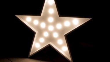 Büyük dekoratif retro yıldız, arka planında yanan bir sürü ışık var. Güzel dekor, modern tasarım öğesi. Çatı katı tarzı stüdyo..