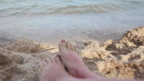 Jambes d'une fille sur la plage. Coucher de soleil en mer, vagues, brise marine, plage . — Video