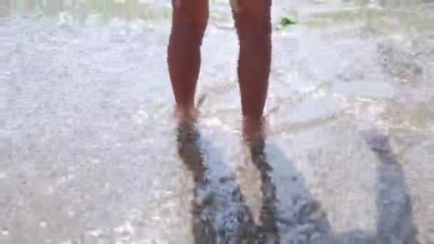 Feliz niño descalzo divertirse en paseo por la playa. Chica correr a lo largo de surf mar junto a la piscina de agua y saltar con salpicaduras. Vacaciones de verano con niños en isla tropical — Vídeo de stock
