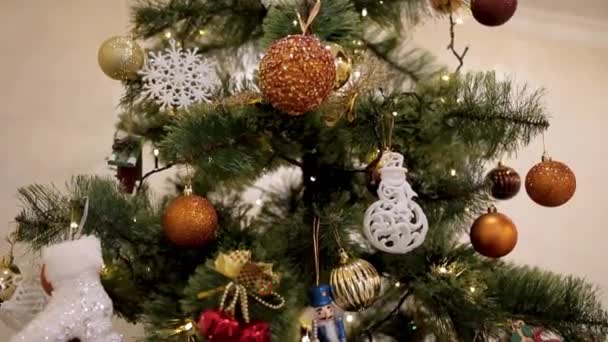 Праздник Рождества. Красиво украшенный дом с елкой. Крупный план цветной безделушки, свисающей с украшенной елки . — стоковое видео