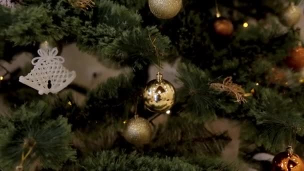 Weihnachtsfest. schön dekoriertes Haus mit einem Weihnachtsbaum. Großaufnahme einer farbigen Christbaumkugel, die an einem geschmückten Weihnachtsbaum hängt. — Stockvideo