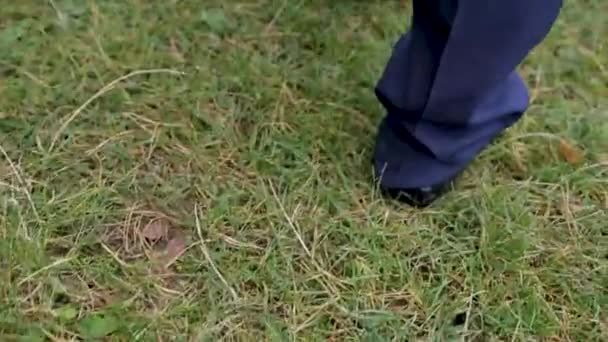 靴で男性の足が草の上行く. — ストック動画