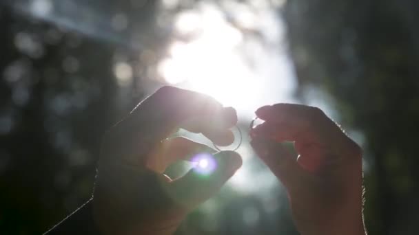 Le mani tengono gli anelli vicini ai raggi del sole. Valorizzare gioielli o sposarsi . — Video Stock