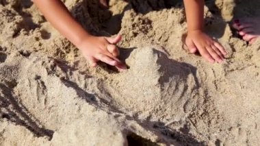 Çocuk yaz sahilinde kumla oynuyor..