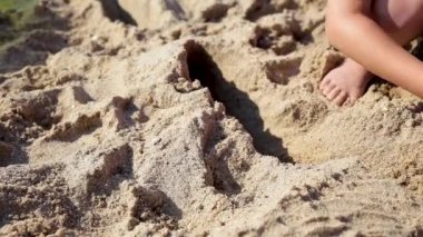 Çocuk yaz sahilinde kumla oynuyor..