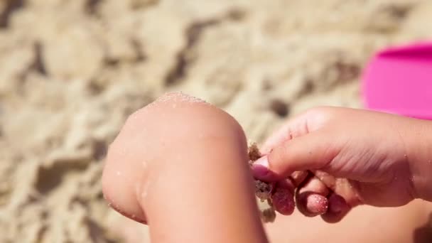 Το παιδί παίζει με άμμο στη καλοκαιρινή παραλία. — Αρχείο Βίντεο