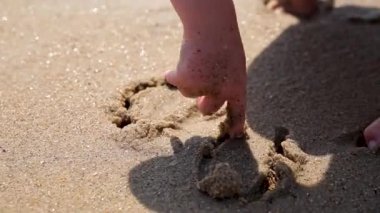 Çocuk parmağını denizkenarındaki kuma çekiyor. Çocuklu aile için deniz tatili. Yaz tatili sırasında egzotik adanın tropik plajda çalışan küçük çocuk.