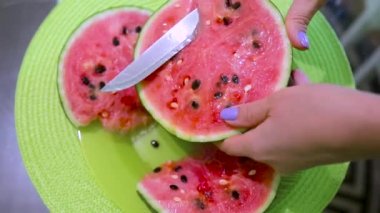 Genç güzel kadın bir masada bıçak karpuz ile keser.