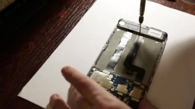 Masabaşında Tornavida ile İnsan Eli Tamir Cep Telefonu Yakın Çekim. Atölyede bozuk akıllı telefonu tamir eden adam. Full Hd