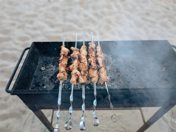 Deniz tarafından kum üzerinde duran bir barbekü bazı ızgara et şişyakın çekim