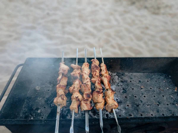 Deniz tarafından kum üzerinde duran bir barbekü bazı ızgara et şişyakın çekim