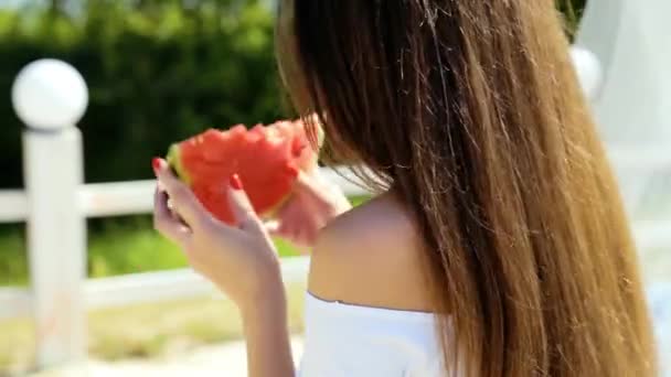 Beautiful, sexy woman, girl with perfect hair and skin poses and eats watermelon on the beach. Rear view. Picnic.