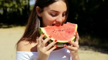 Güzel, seksi kadın, mükemmel saç ve cilt ile kız pozlar ve plajda karpuz yiyor. Piknik.