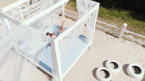 Exquise meisje met haar kleine dochter ontspannen en spelen in bungalows op het strand. — Stockvideo