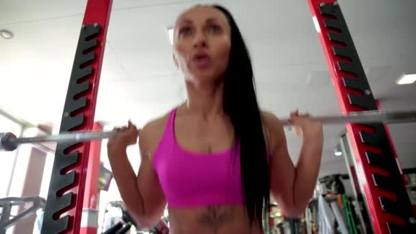 Młoda kobieta przysiada ze sztangą na siłowni. — Wideo stockowe