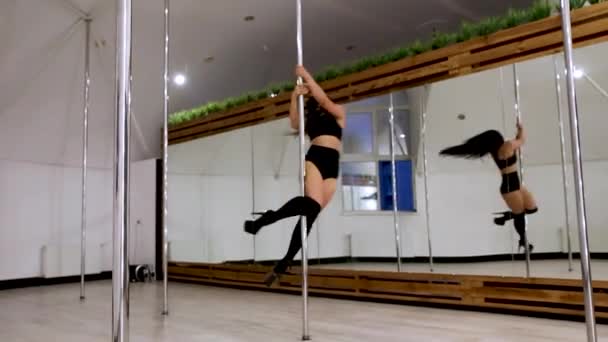 Uma jovem mulher em uma máscara preta dança pole dance no salão para pole dance durante coronavírus quarentena, covid 19. — Vídeo de Stock