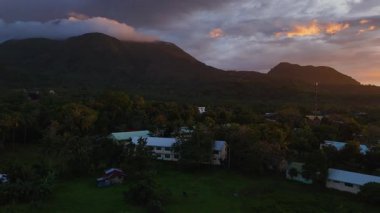 Camiguin adası üzerindeki tropikal günbatımını, volkanik manzarayı ve geniş okyanusu gösteren hava aracı görüntüsü, karamsar sözleşmeli gökyüzü Filipinler Asya Tatil Turizmi 