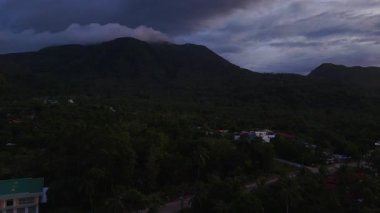 Camiguin adası üzerindeki tropikal günbatımını, volkanik manzarayı ve geniş okyanusu gösteren hava aracı görüntüsü, karamsar sözleşmeli gökyüzü Filipinler Asya Tatil Turizmi 