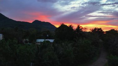 Camiguin adası üzerindeki tropikal günbatımını, volkanik manzarayı ve geniş okyanusu gösteren hava aracı görüntüsü, karamsar sözleşmeli gökyüzü Filipinler Asya Tatil Turizmi 