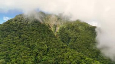 Yeşillik yeşil orman örtüleri ve kasvetli bulutlarla volkanik dağ sıraları ve buğulu Hibok Hibok Ulusal Parkı Filipinleri, Camiguin Adası Asya turizm beldesi Sinematik 