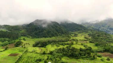 Yeşillik yeşil orman örtüleri ve kasvetli bulutlarla volkanik dağ sıraları ve buğulu Hibok Hibok Ulusal Parkı Filipinleri, Camiguin Adası Asya turizm beldesi Sinematik 
