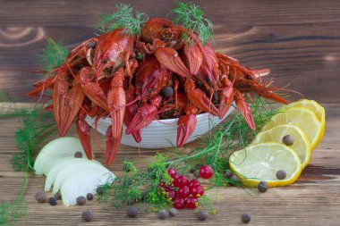 Pençeleri ve rezene, soğan, limon ve biber ahşap arka plan üzerinde kırmızı haşlanmış crayfishes tabak