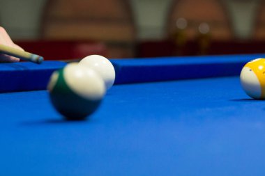 Bilardo oyunu devam ediyor, oyuncu ıstakayla topa vurmayı hedefliyor
