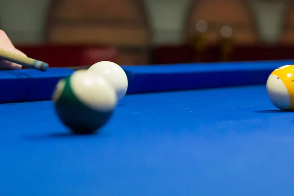 Billiard pool game in progress, player aims to shoot balls with cue