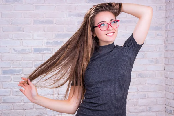 Chica joven en gafas rojas tira de su cola de pelo largo Fotos de stock