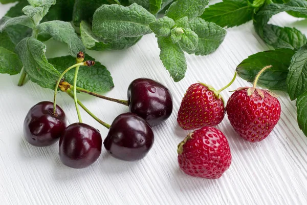 Weinkirschen, rote Erdbeeren, grüne frische Minze und Melisse — Stockfoto