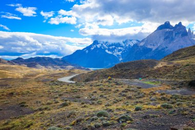 Şili 'deki Torres del Paine Ulusal Parkı' ndaki dağlara giden uzun ve güzel bir yol.