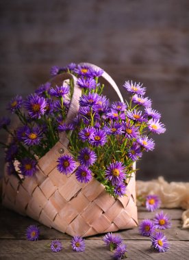 Ahşap bir masada beyaz bir sepetin içinde mavi çiçeklerle dolu bir hayat..