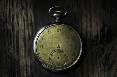 Tahta bir arka planda dakikası ve saati olmayan antika gümüş bir saat..